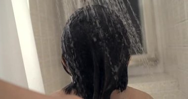 Duşun altında duran çocuk, su akışı, arka manzara, ıslak saçlar, yüksek hız yakalama, yavaş çekim detayı, banyo sahnesi, ferahlatıcı an, duş alma deneyimi, temiz su damlacıkları.