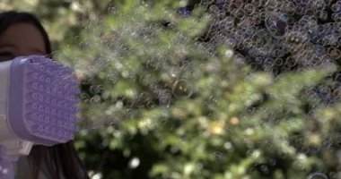 Kabarcık makinesini kullanarak 800 fps hızla kabarcıklar oluşturan bir kız. Havayı dolduran kabarcıklar gibi gülümseyen, sihirli ve eğlenceli bir açık hava yaratıyor.