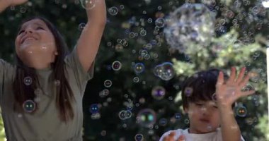 Bir erkek ve kız 800 fps yavaş çekim kabarcıklar zevk, kolları havada kız, her ikisi de renkli kabarcıklar arasında bir şelale arasında gülümsüyor açık hava ayarı