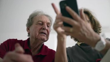 Akıllı telefonu birlikte kullanan yaşlı bir çift, ekrana bakan bir erkek, teknolojiyle ilgilenen bir kadın, yaşlılar yaşam tarzı, dijital öğrenme, modern cihazlar, cihazlarla bağlanma, kapalı mekan sahnesi