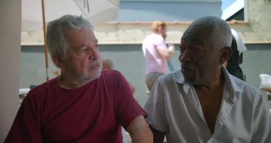 İki yaşlı arkadaş arka bahçedeki barbekü partisinde kahkaha ve sohbet ediyorlar. Canlı bir açık hava toplantısında neşe, bağlantı ve dostluğu somutlaştırıyorlar.