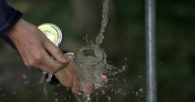 Eller açık havadaki musluktan gelen suyla etkileşime girer, kavanozu temizler, yavaş çekimde su sıçratır, temizliği ve ferahlığı ön plana çıkarır.