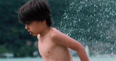 Suyun tadını çıkaran bir çocuk, yaz oyununun coşkusunu ve heyecanını gözler önüne seriyor, 800 fps 'de yavaş çekim görüntüsü.