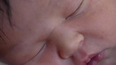 Yeni doğmuş bebek yüzünün makro yakın çekimi ve hayatın ilk günlerinde minik eller. Varlığının ilk haftasında bebek..