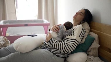 Yorgun bir anne, yeni doğmuş bir bebekle yatakta yatar, hayatının ilk günlerinde göğsünde uyur, anne öğleden sonra kestirir, anne bakımı yapar..