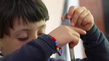 Küçük çocuk spagettiyi çatalla çevirmekle meşgul, kararlı bir ifadeyle, sıcak, ev ortamında yemek saatinde konsantrasyon ve çabayı vurguluyor.