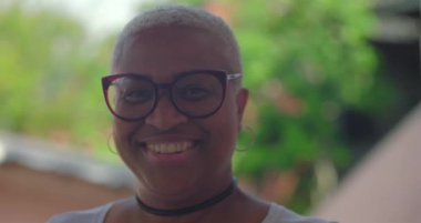 Gülümseyen kıvırcık saçlı, siyah gömlekli, kendine güveni ve neşe saçan, yeşil, sıcak ve dost canlısı, güler yüzlü genç İspanyol çocuk.