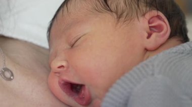 Bebeğin İlk Günleri - Erken Yaşamda Anne Göğsünde Huzur içinde Uyumak, şirin bir ifadeyle yeni doğan bebeğin yakın plan yüzü.