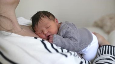 Yeni doğan bebek annesinin göğsünde dinleniyor. Yaşamın ilk günlerinde sevgi ve annelik bakımıyla sarılıp uyuyor..