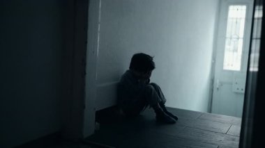 Beş yaşındaki çocuk duygusal umutsuzlukla boğuşuyor, karanlık koridorda tek başına oturuyor, elleriyle yüzünü kaplıyor, çocukluk bunalımı kavramsallaşmış.