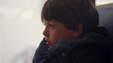 Hareket halindeki bir otobüsün penceresinde oturan genç çocuk, derin düşüncelere dalmış, sessizce geçen manzarayı seyrediyor.