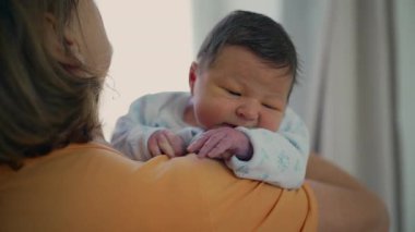 Büyükannesi yeni doğan torununu omzunda tutarak sıcak ve rahat bir ortam sağlıyor. Bebeğin nazik tutuşu ve barışçıl ifadesi aralarındaki sevgi ve bağı yansıtıyor.