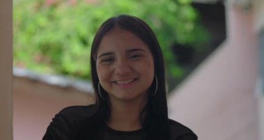 Uzun siyah saçlı ve halka küpeli genç bir kız. Sıcak bir şekilde gülümsüyor. Kendine güvenen bir birey.