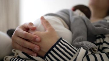 Annenin yeni doğmuş bebeğini uyurken göğsüne yakın tutarken çekilmiş bir fotoğrafı. Yavrularla el ele tutuşurken çekilmiş.