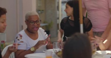 Bir grup arkadaş gülerek ve dışarıda eğlenerek, güneşin altında coşkulu bir şekilde toplanan, bağın, kutlamanın ve sevincin altını çizerek