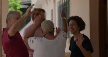 Bir grup farklı arkadaş, hareketli bir açık havada dans ediyor. Topluluğu, eğlenceyi ve birlikteliği kutluyorlar. Sıradan ve neşeli bir atmosferde.