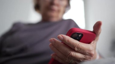 Üst düzey kadın elinde akıllı telefon cihazıyla içeriği okuyor, 70 'lerin yaşlı kadını okuma gözlüğü takıyor ve iletişim için telefon teknolojisini kullanıyor.