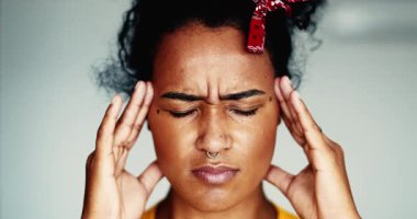 Genç, hayal kırıklığına uğramış, yakın plan bir kadın, baş ağrısı çekiyor, ellerini şakaklarına koyuyor, zihinsel baskı hissediyor. 20 'li yaşlarda Afro-Amerikan olan