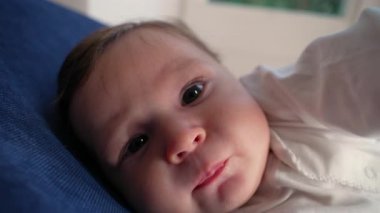 Bebek garip bir ifadeyle uzanıyor, hareketleri keşfediyor, erken çocukluk gelişimini keşfediyor, dokunuşu keşfediyor, yüz konsantrasyonunu, bağlılığı, duyusal farkındalığı, ev dekorasyonunu,