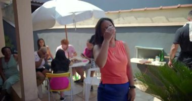 Arka bahçedeki bir barbeküde neşeyle gülen bir kadın, dışarıda canlı bir toplanma sırasında bir mutluluk anı yakalıyor ve aile ve arkadaşlarla bağlantı kuruyor.