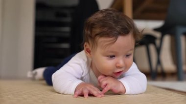 Bebek göbek üstü yatıyor, kollar açık, heyecanlı ifade, ağız açık, istekli hareket, emekleme pratiği, erken çocukluk gelişimi, keşif, ev dekorasyonu