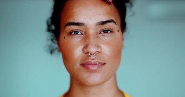 Bir genç siyah Latin kadın kameraya tarafsız bir ifadeyle bakıyor. 20 'li yaşlarda, Afrika kökenli, yakın plan yüzlü bir Güney Amerikalı kadın.