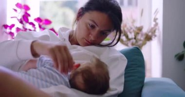 Anne, anne ve çocuk arasında şefkatli ve sevgi dolu bir ortamda bebeğini emzirirken nazikçe başını okşuyor..