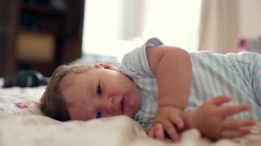 Yatakta uzanan bebek, sakin ifade, çevreyi keşfetme, yumuşak ve rahat an, erken çocukluk gelişimi, nazik merak, huzurlu ev atmosferi