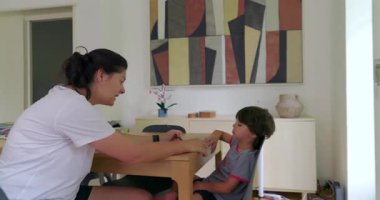 Anne ve oğlu evde bir eğitim seansına katıldı, anne çocuğuna eğitim materyallerini anlatıyor.