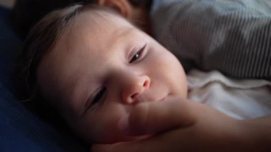 Bebek kardeşlerin kucağında dinleniyor, hassas bir an, nazik bir dokunuş, sakin bir ifade, güvenli aile bağı, çocukluk masumiyeti, duygusal bağ, sevgi, sıcaklık..