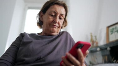 Üst düzey kadın elinde akıllı telefon cihazıyla içeriği okuyor, 70 'lerin yaşlı kadını okuma gözlüğü takıyor ve iletişim için telefon teknolojisini kullanıyor.