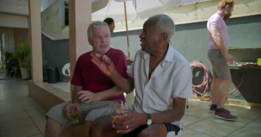 İki yaşlı arkadaş arka bahçedeki barbekü partisinde bira bardaklarını tokuşturuyor, neşeli ve canlı bir açık hava toplantısında dostluğu ve bağlantıyı kutluyorlar.