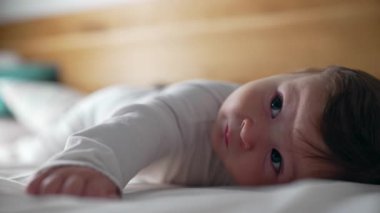 Bebek karnının üstünde yatıyor, neşeli bir ifade, başını kaldırırken gülümsüyor, erken gelişim, karın ağrısı, kasları güçlendirme, çocukluk merakı, neşeli bir an, ev dekorasyonu.