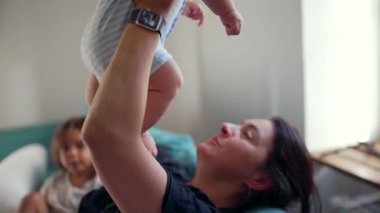 Anne kucağında bebek, yatakta yatarken sevgi dolu bakışlar, ebeveyn-çocuk bağı, sıcaklık, bağlantı, sevgi, güven, aile sevgisi, nazik kucaklama, şefkat..