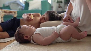 Bebek yerde yatar, kolunu uzatır, kardeşinin yemek yemesine, sessiz gözlemlere, erken duyusal keşiflere, sıcak aile bağlarına, huzurlu yuvalara bakar..