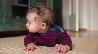 Bebek karnında yatıyor, heyecandan gülümsüyor, emekleme evresinde, neşeli ifade, bebek gelişimi, merak, neşeli an, ev ortamı, büyüme, mutluluk