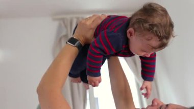 Anne neşeli bir kahkaha ile bebeği kaldırma, neşeli bir bağ, ebeveyn-çocuk bağı, mutluluk, güven, sıcaklık, sevgi, sevgi, aile sevinci, güvenlik.