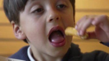 Çocuk aniden ağzından sıcak bir kızartmayı çekip çıkardı. Şaşırdığını ve rahatsız olduğunu ifade etti. Sıcak yemek tatma anı yakalar, duyusal deneyimi ve tepkiyi ön plana çıkarır..
