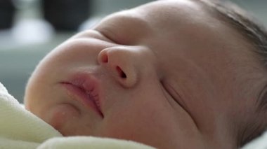 Yeni doğmuş bir bebeğin huzurlu uyuyan yüzüne yakın çekim yapmak, hassas özellikleri ve barışçıl ifadesini vurgulamak. Yumuşak ışık, bebeğin pürüzsüz cildini ve huzur dolu tavırlarını güçlendirir. Saf masumiyet anını.