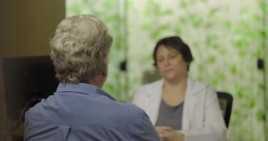 Sağlık hizmetleri danışmanlığı sırasında tıbbi muayenede erkek hasta kadın doktorla konuşuyor. Arka plan ve profesyonel klinik ortamlara odaklanıyor.