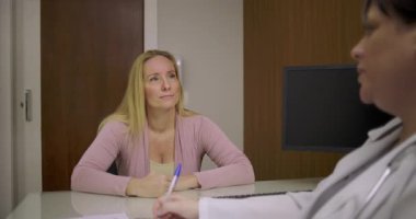 Özel klinik ortamında dostane sağlık danışmanlığı sırasında gülümseyen ve doktoru dinleyen orta yaşlı bir hasta.