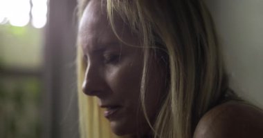 Kadın, sağlık hizmetleri ortamını yansıttığı bir anda, gözleri kapalı, tek başına zor duyguları sindirmeye çalışıyor.