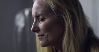 Acı dolu ifadesi ve kapalı gözleri olan bir kadının yakın çekimi, tedavi sırasında duygusal bir an veya tıbbi ortamdaki teşhis.