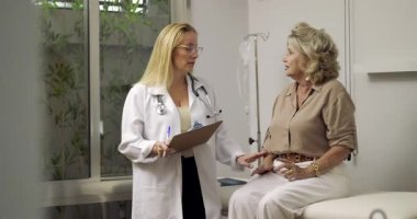 Kadın doktor, klinikteki kontroller sırasında klinikteki yaşlı kadın hastaya tıbbi bilgileri açıklıyordu.