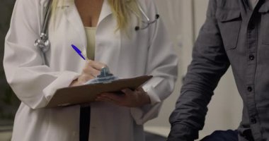 Profesyonel bir iç sağlık hizmetleri ortamında tıbbi danışma sırasında hastanın yanındaki panoya notlar yazan doktorların yakın çekimleri