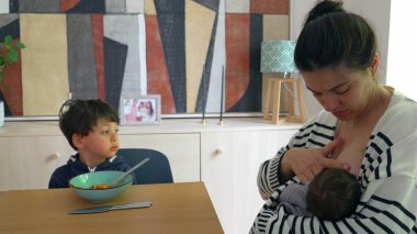 Kadın, bebeğini rahat bir evde emzirirken oğluna spagetti yediriyor ve aynı anda birden fazla çocuğa bakan bir annenin yoğun hayatını anlatıyor.