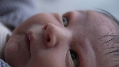 Yenidoğan 'ın yüzü, gözleri tamamen açık, erken yaşların merak ve masumiyeti, hassas cildini ve bebeğin yüz hatlarının ince detaylarını vurguluyor.