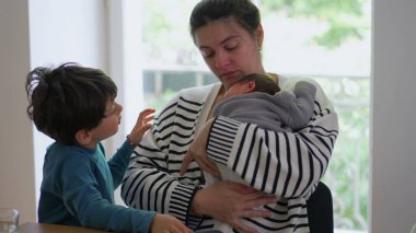 Anne hem yeni doğan hem de büyük çocuğunu yanında tutarak aile içinde paylaşılan sıcaklığı, sevgiyi ve bağlantıyı vurgulayan samimi ve huzurlu bir aile anı yaratıyor.