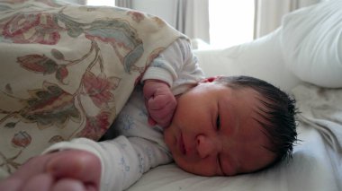 Çiçekli bir battaniyenin altında uzanan yeni doğmuş bebek, gözleri nazikçe kapalı, huzurlu ve güvenli bir çevreyi taşıyor, bebeklik, rahatlık ve yaşamın ilk aşamaları için mükemmel.