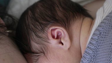 Yeni doğmuş bir bebeğin kulağı annelerinin göğsüne dayanmış, hassas samimiyetlerini ve bağlarının sıcaklığını vurguluyor. İlk anne bozuntusunda yakınlık ve bağlantı 480p